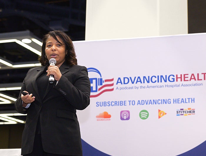 A speaker infront of an Advancing Health Podcast sign