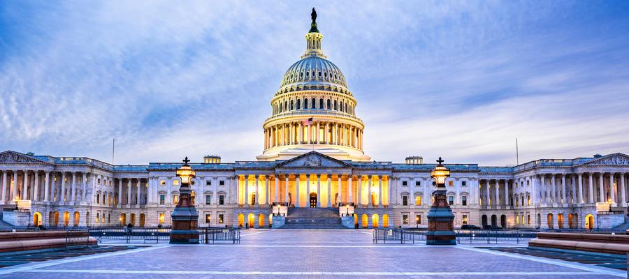 US Capitol lit at dusk across visitors plaza