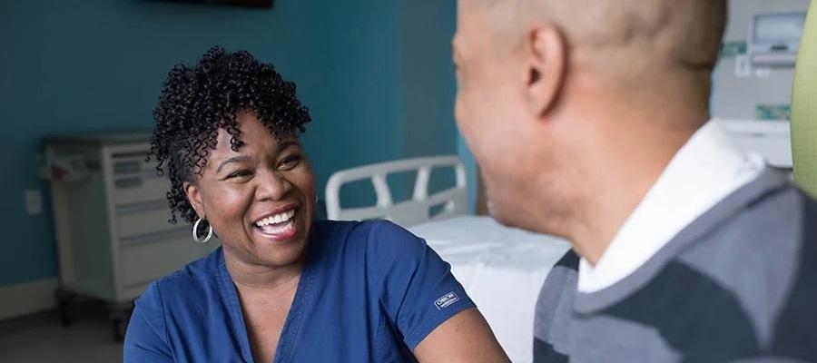 Study shows successful use of immunotherapy drug instead of traditional options to treat cancer. A nurse happily speaking with a cancer patient after successful immunotherapy drug treatment.